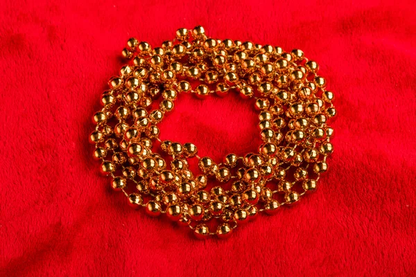 Christmas golden beads on red background — Stock Photo, Image