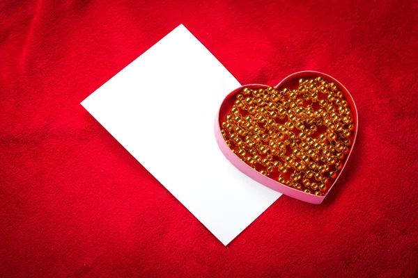 Corazón con una tarjeta en blanco sobre fondo rojo —  Fotos de Stock