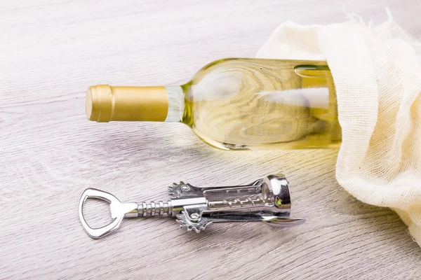 Fles wijn met corkscrew op houten achtergrond — Stockfoto