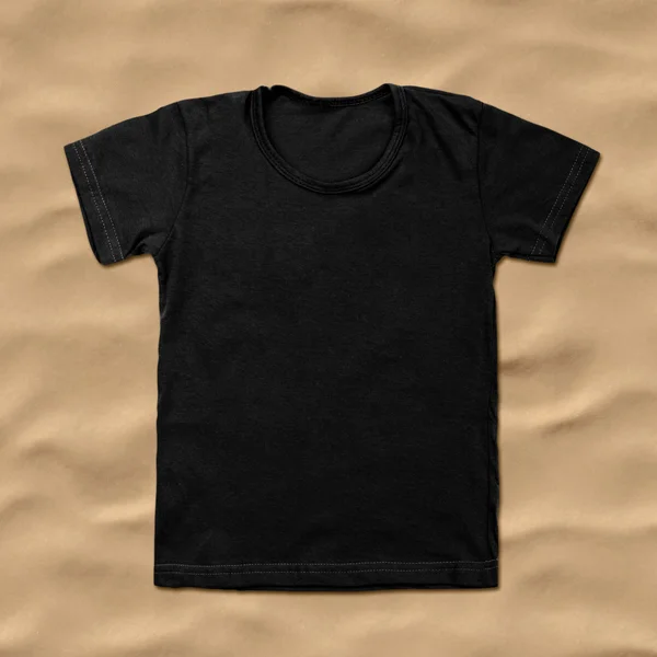 Black blank t-shirt on sand background — Stock Photo, Image