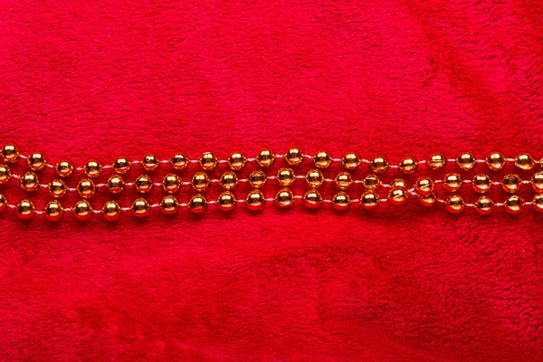 Christmas golden beads on red background — Stock Photo, Image