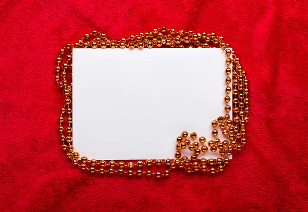 Christmas golden beads on red background — Stock Photo, Image