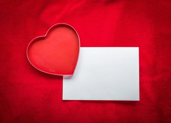 Сердце с пустой карточкой на красном фоне — стоковое фото