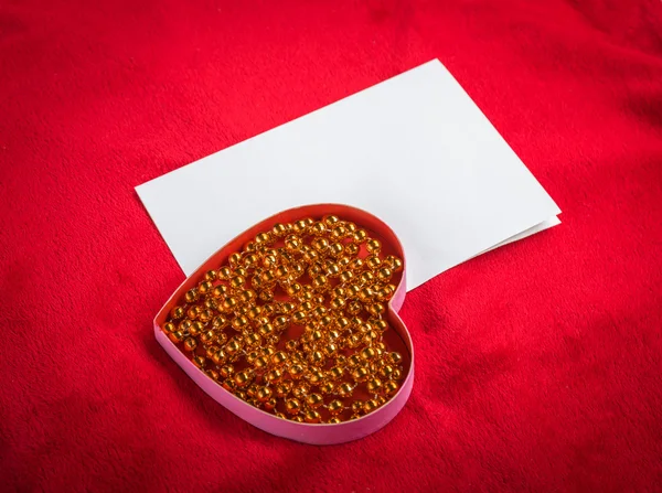 Coração com um cartão em branco no fundo vermelho — Fotografia de Stock