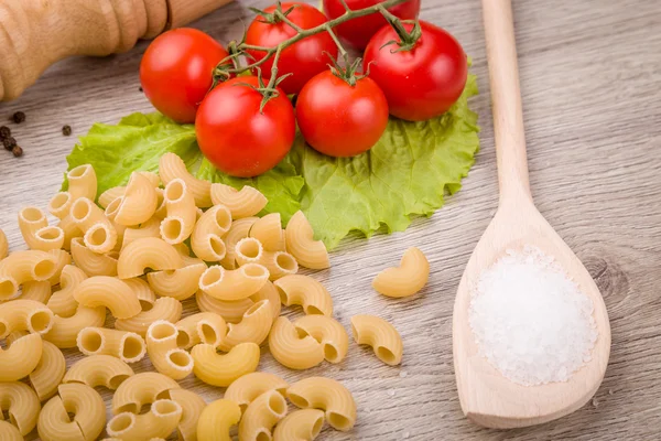 Massas, tomates e pimenta em um fundo de madeira — Fotografia de Stock