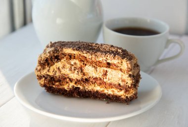 Beyaz tabakta çikolatalı kek ve bir fincan çay