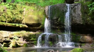 Kafkasya 'nın güneşli yaz ormanlarında küçük bir gölü olan pitoresk bir şelale.