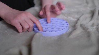 Çocuk anti-stres mor pop it kıpırdayan oyuncağıyla oynuyor. Yakınlaştır, basit gamzeler, duyusal çocukların ve yetişkinlerin oyuncaklarının kullanımı motor beceriler için, strese karşı