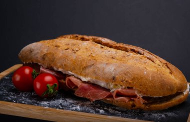 Krem peynirli Ciabatta sandviçi ve ahşap tepside jambon.