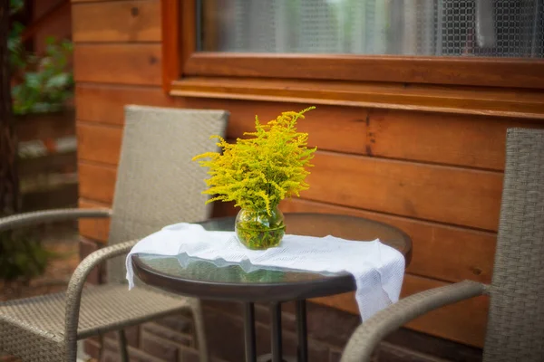 Solidago - wild flowers, also called goldenrods. Bouquet of yellow flowers in the glass vase. Rest outside the city