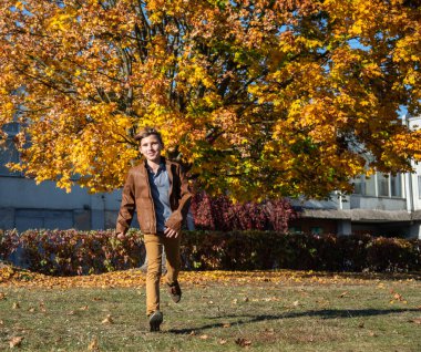 Sonbahar parkında koşan tatlı çocuk. Güneşli bir günde sonbahar parkında bir erkek çocuğunun portresi. Mutlu çocukluk yaşam tarzı konsepti