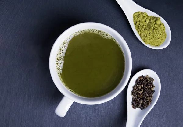 Grüner Tee in einer Tasse auf schwarzem Hintergrund — Stockfoto