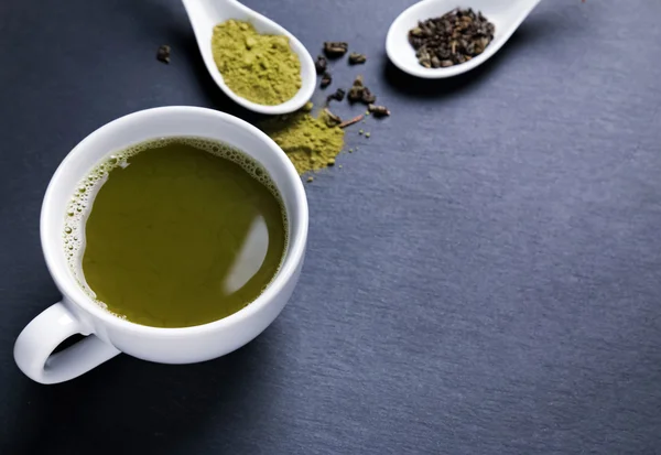 Grüner Tee in einer weißen Tasse auf schwarzem Hintergrund — Stockfoto