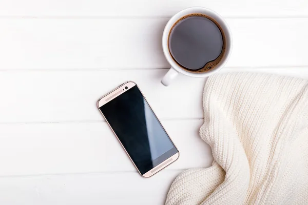 Kahve, telefon ve beyaz masanın üzerine örme kazak — Stok fotoğraf