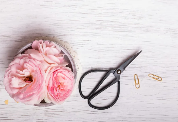 Nůžky na dřevěný stůl bílé a růžové květy — Stock fotografie