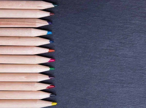 Colorful wooden pencils on the black board — Stock Photo, Image