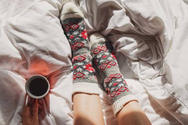 Bir fincan kahve ya da çay ve kadın ayaklarıyla sıcak örgü çorap.