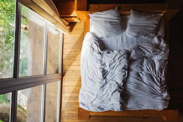 Кровать с белым постельным бельем в деревянном рустикальном домике — стоковое фото