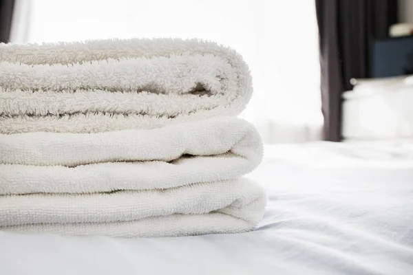 Stack of clean fluffy white towels on the bed — Stock Photo, Image