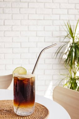 Beyaz masada buz küpleri olan bir bardakta espresso toniği.