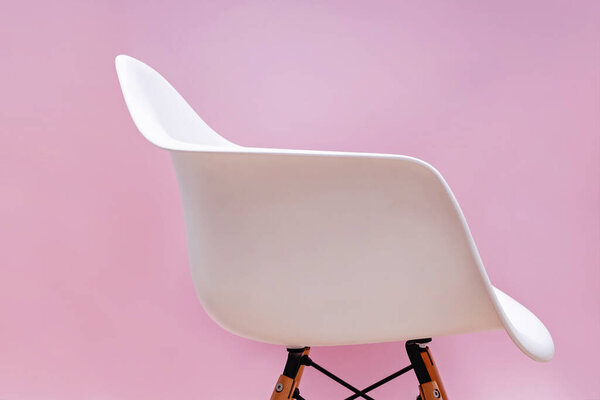 White contemporary chair over pink wall.