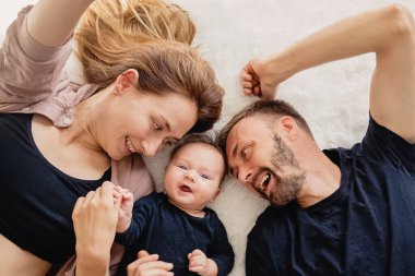 Genç anne, baba ve halıya uzanmış küçük tatlı oğlu.