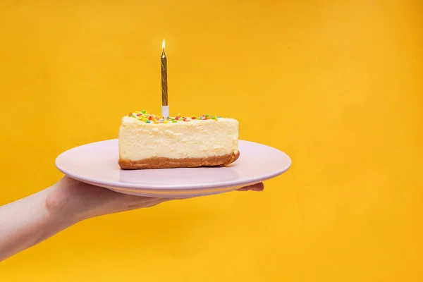 Hand holding a piece of birthday cake on the plate — Stock Photo, Image