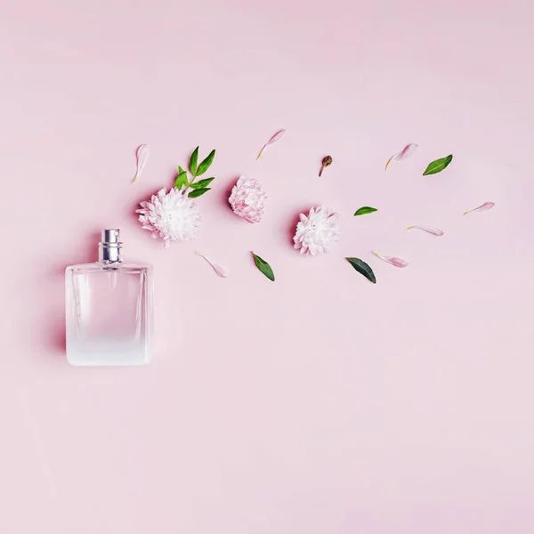 Uma garrafa de perfume, flores e pétalas sobre fundo rosa. — Fotografia de Stock