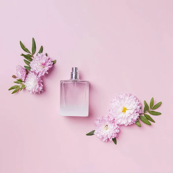 Uma garrafa de perfume, flores e pétalas sobre fundo rosa. — Fotografia de Stock