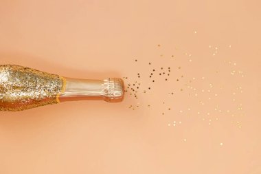 Altın parıldayan şampanya şişesi ve yıldız şeklinde konfeti.