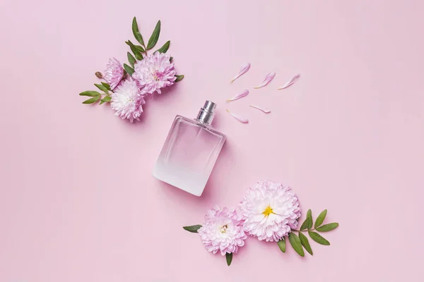 Uma garrafa de perfume, flores e pétalas sobre fundo rosa. — Fotografia de Stock