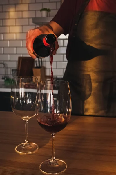 A man pours red wine into a glass — Stock Photo, Image