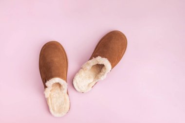 Pembe arka planda sıcak süet terlikler.