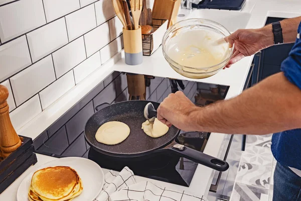 Чоловік готує млинці на своїй сучасній кухні — стокове фото