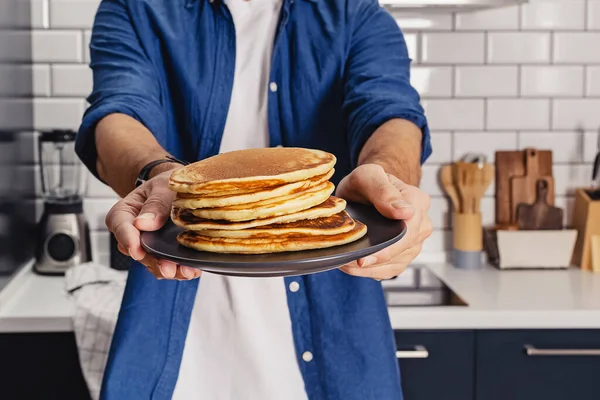 Man holds a stack of fresh baked pancakes — Stock Photo, Image