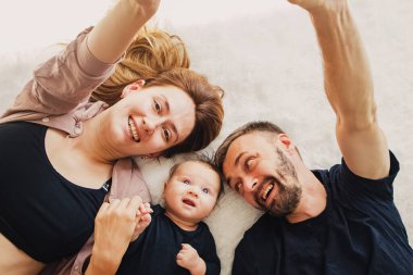 Anne, baba ve küçük sevimli oğulları halının üzerinde yatıyor.