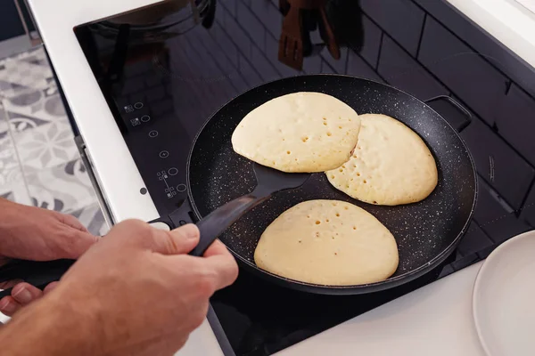 Man frying pancakes on the pan at his kitchen. — Stock Photo, Image