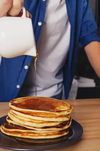 Man pouring with maple syrup on the stack of pancakes — Stock Photo, Image