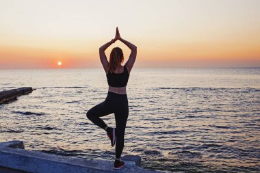 Deniz kenarında egzersiz yapan genç bir kadın.