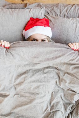 Yataktaki kadın yüzünü Blanke ile örten kırmızı bir şapka takıyor.