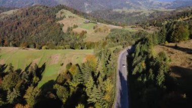 Sonbahar dağlarına giden hava aracı görüntüsü ve yolda giden araba.