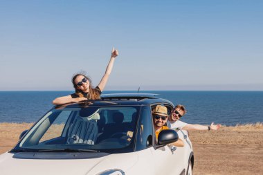 Mutlu, gülümseyen canavarlar denizin yanındaki arabada..