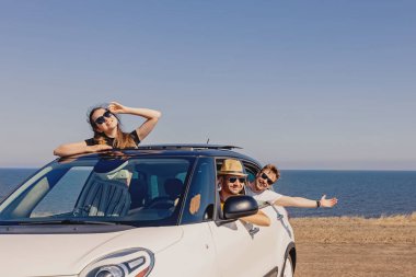 Mutlu, gülümseyen canavarlar denizin yanındaki arabada..