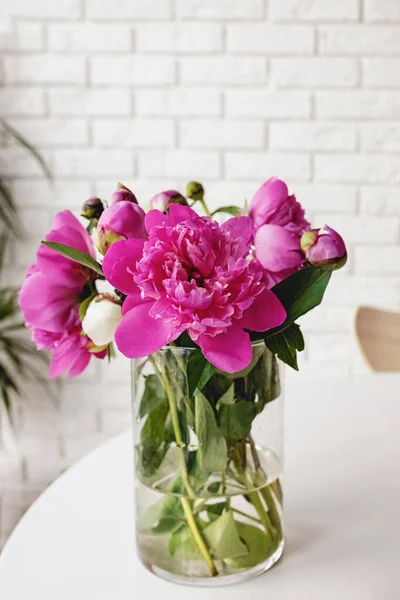 漂亮的一束亮晶晶的粉红花瓣插在白桌上的花瓶里 — 图库照片