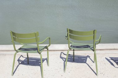 Tuileries bahçesinde iki boş yeşil metal sandalye.