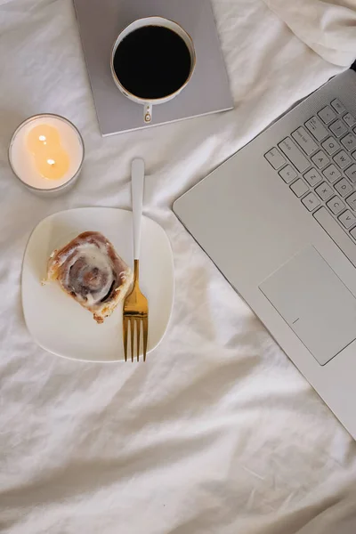 Composizione stile di vita con panino alla cannella, caffè, candela accesa e laptop — Foto Stock