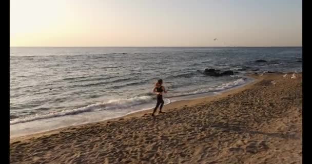 Prise de vue aérienne d'une jeune femme faisant du jogging sur une plage — Video