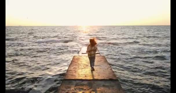 海の石の桟橋で新しい日に向かって実行している若い女性のスローモーションショット — ストック動画