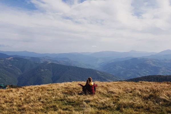 Kobieta siedząca w pozycji do medytacji spoglądająca na szczyty gór — Zdjęcie stockowe