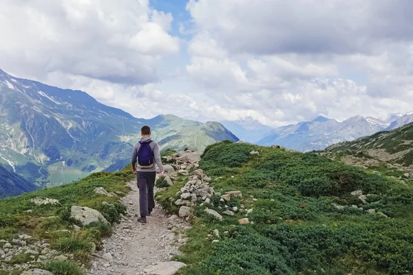 Homem com uma mochila caminhando nas montanhas de verão. — Fotografia de Stock